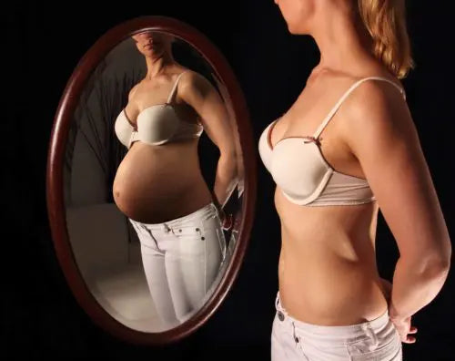 Femme devant miroir qui croit qu'elle est enceinte