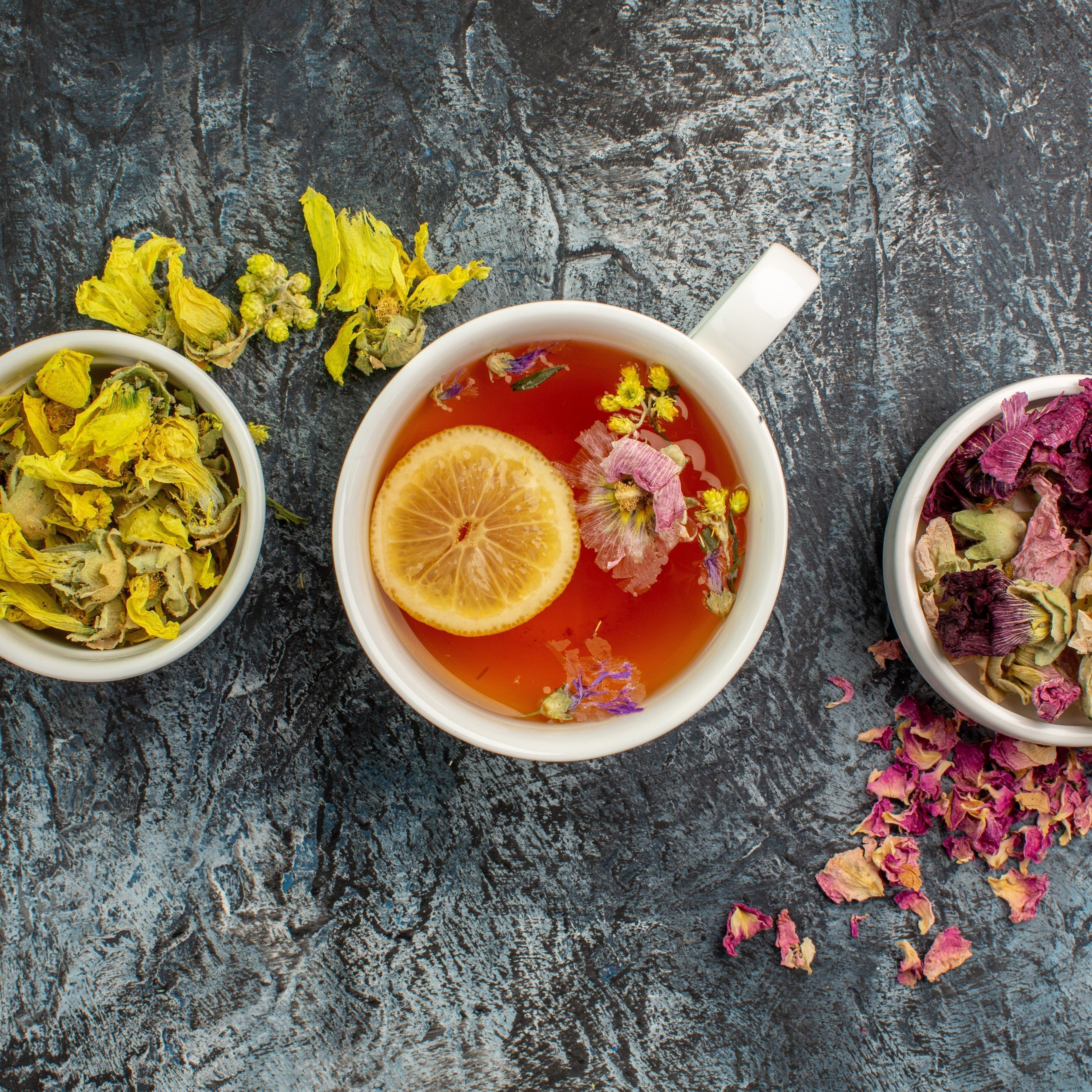 Tasses de thé avec des feuilles et fleurs sur fond gris